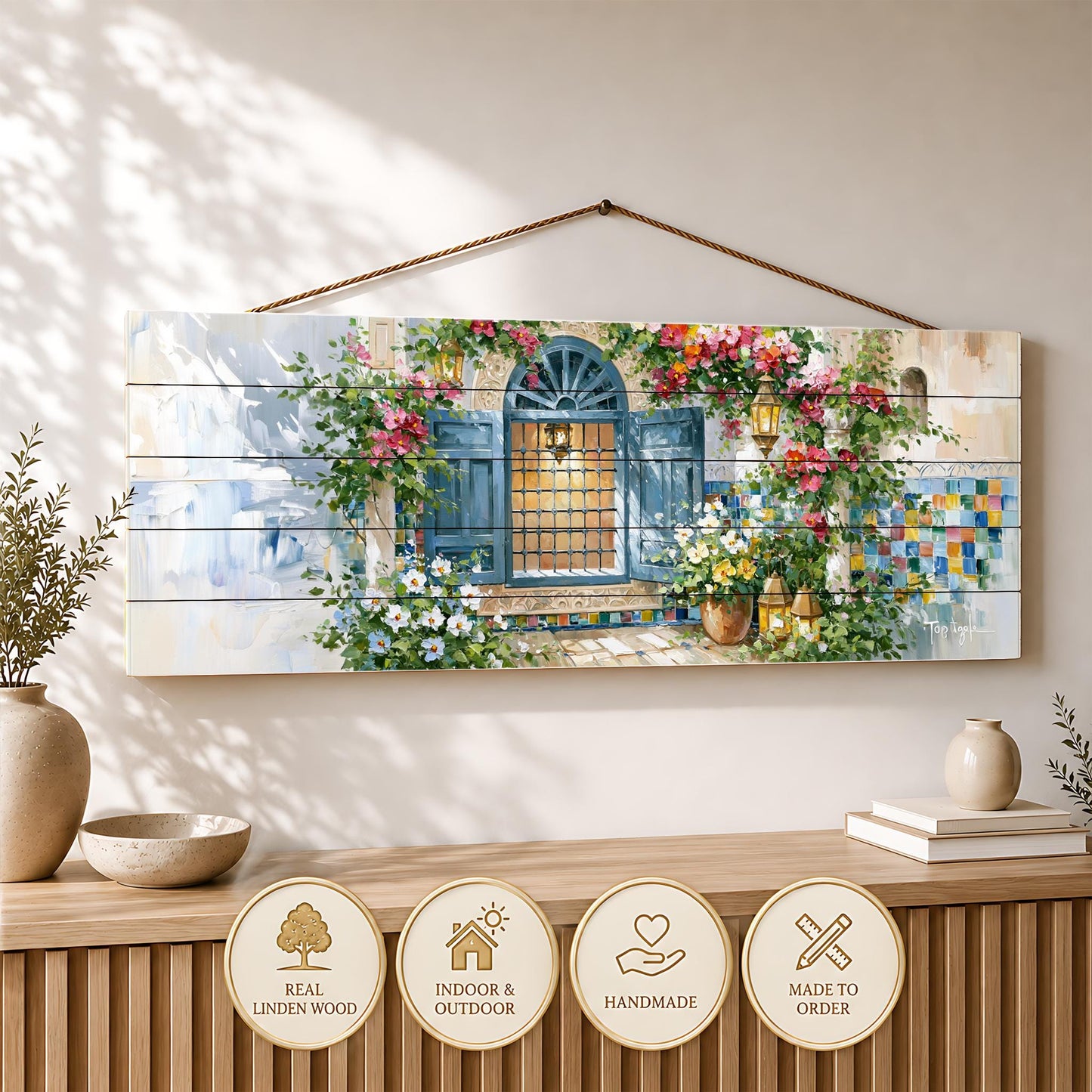 a wooden wall hanging with a painting of a colorful, flower-filled window. The painting is hanging on a wall, and there are several decorative items placed below it, including a vase, a bowl, and a stack of books.