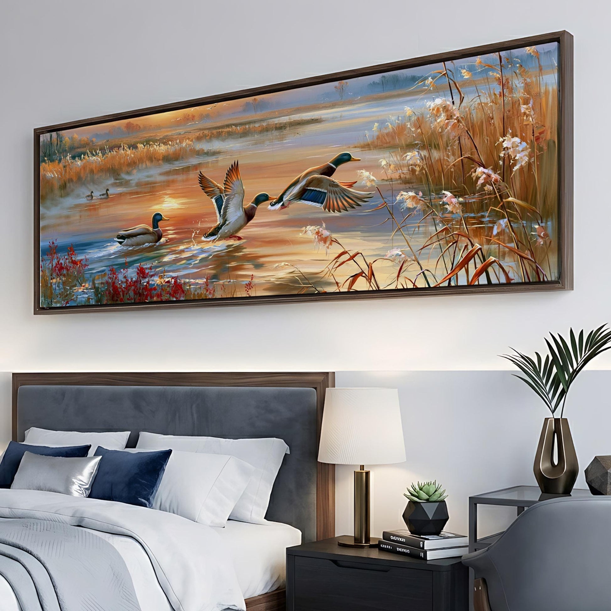 a large painting of ducks swimming in a pond, hanging on a wall above a bed with a gray headboard.