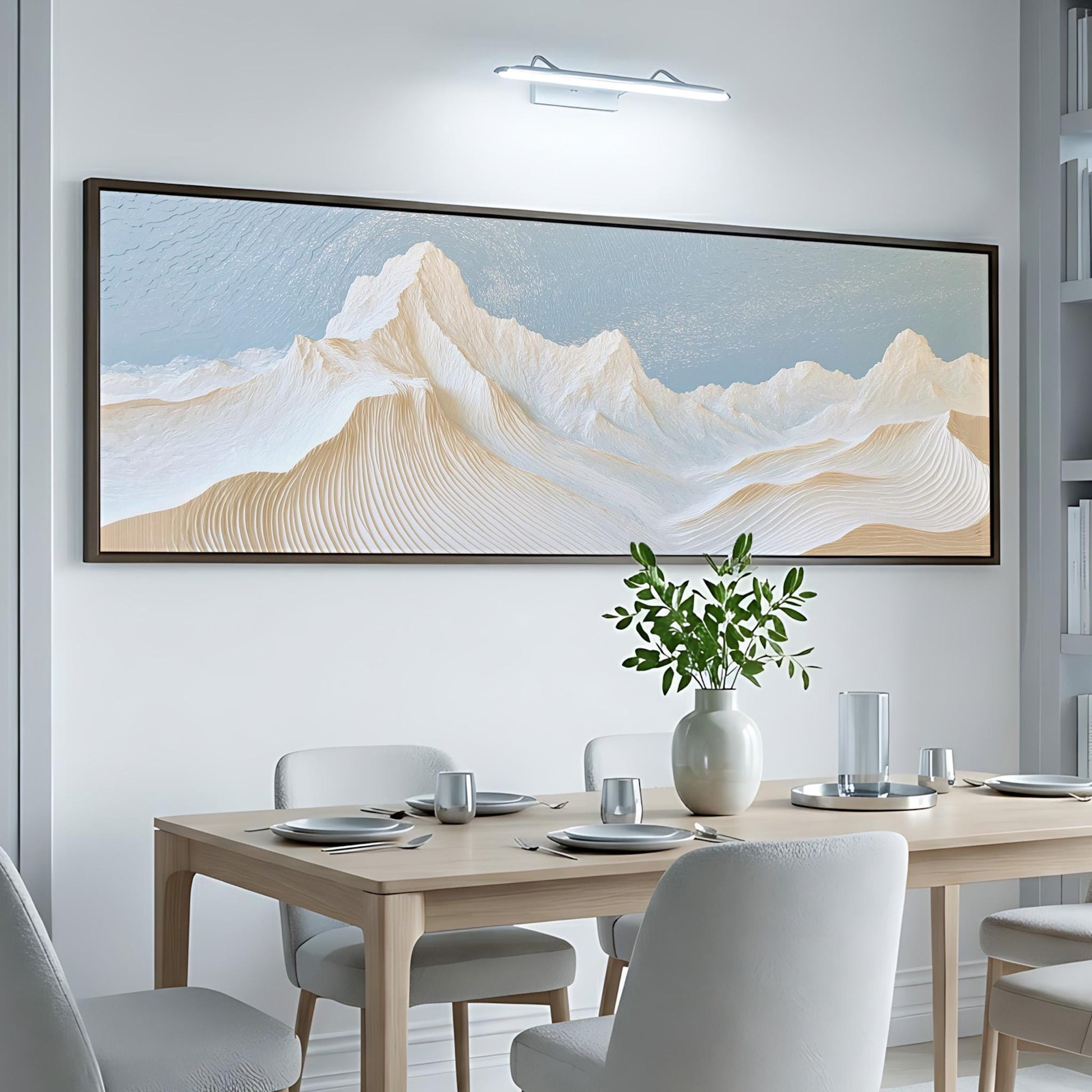 a dining room with a large, framed painting of a mountain landscape hanging on the wall above a wooden dining table set with plates, silverware, and a vase of greenery.