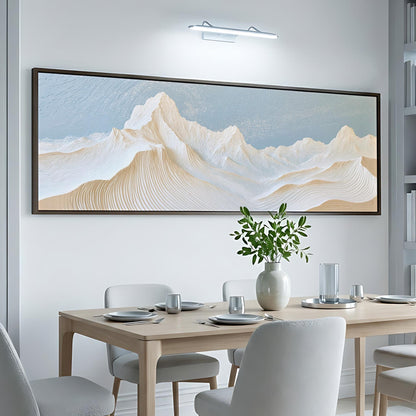 a dining room with a large, framed painting of a mountain landscape hanging on the wall above a wooden dining table set with plates, silverware, and a vase of greenery.
