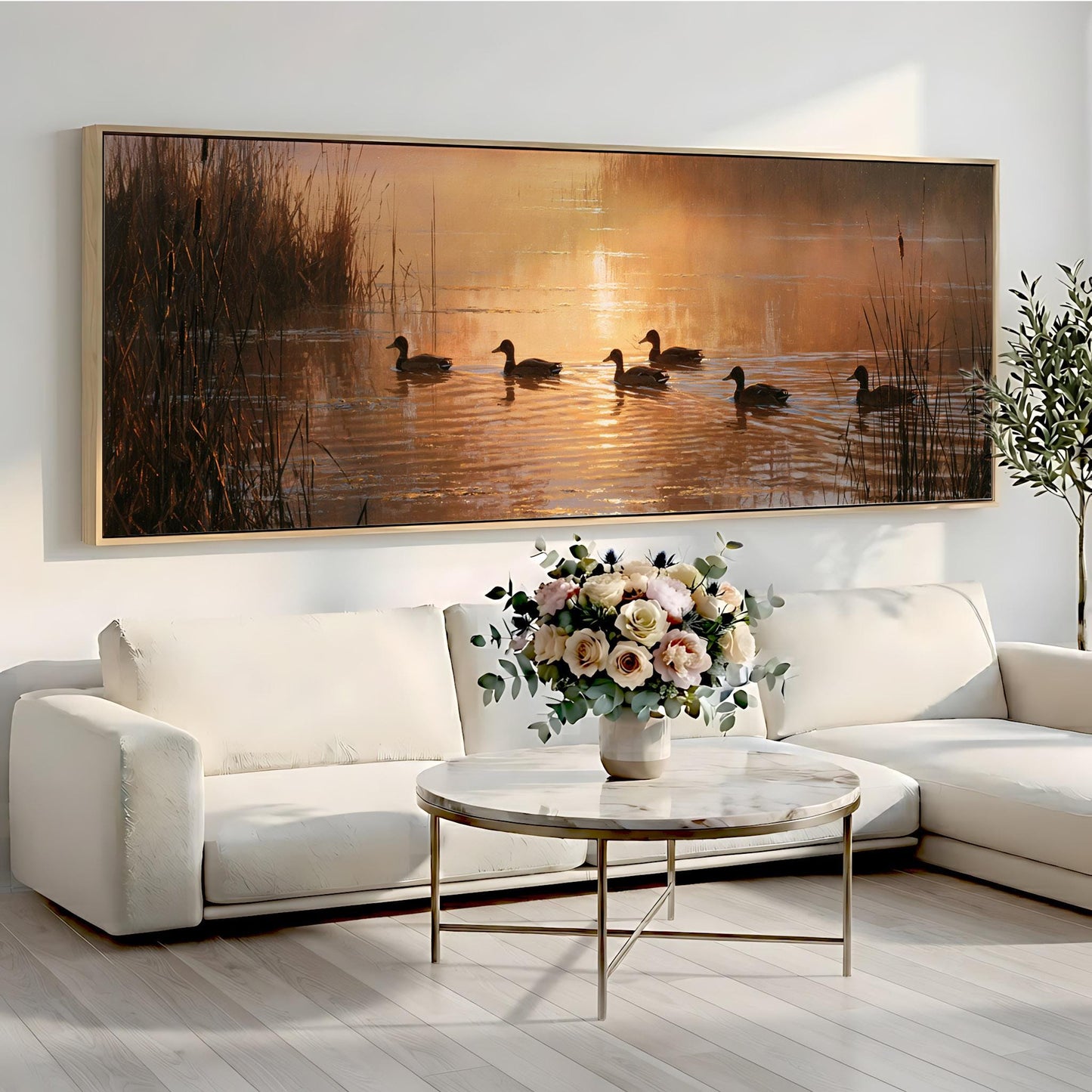 a large painting of ducks swimming in a pond, with a vase of flowers on a coffee table in front of a white sofa.