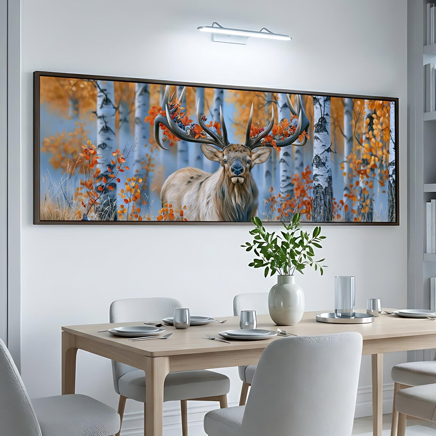a large, framed painting of a deer with antlers in a forest setting, hanging on a white wall above a dining table with chairs.