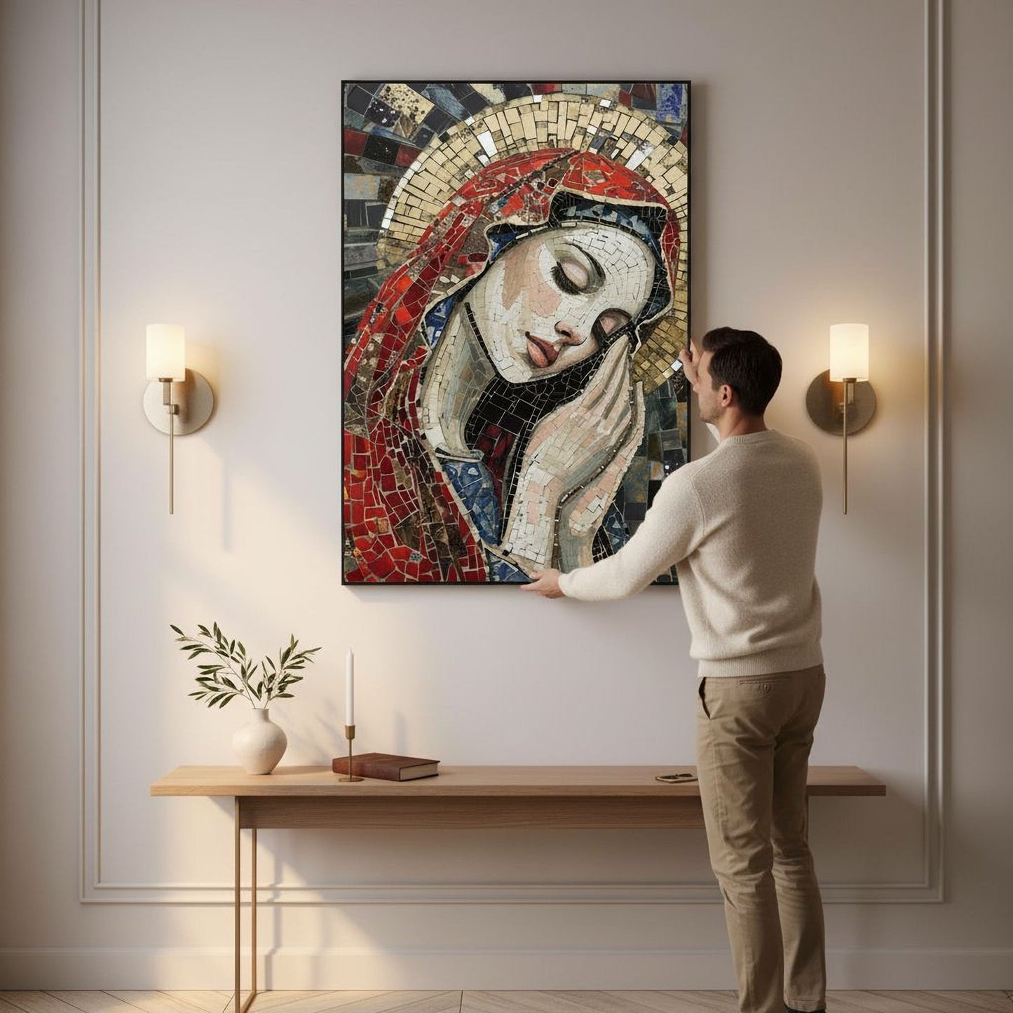A man is standing in front of a large mosaic artwork depicting a woman's face, touching the painting. The artwork is mounted on a wall above a wooden table with a vase and a book on it.