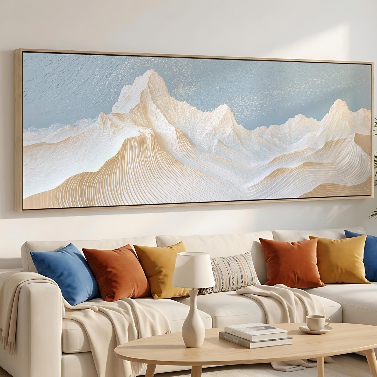 a large, framed painting of a mountain landscape hanging on a wall above a white sofa with colorful throw pillows.