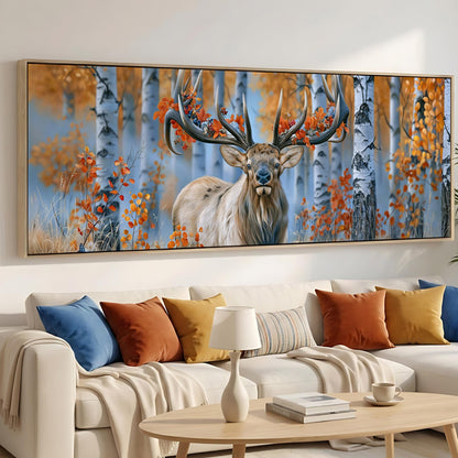 a large painting of a deer with antlers in a forest setting, hanging on a wall above a white couch with colorful throw pillows.