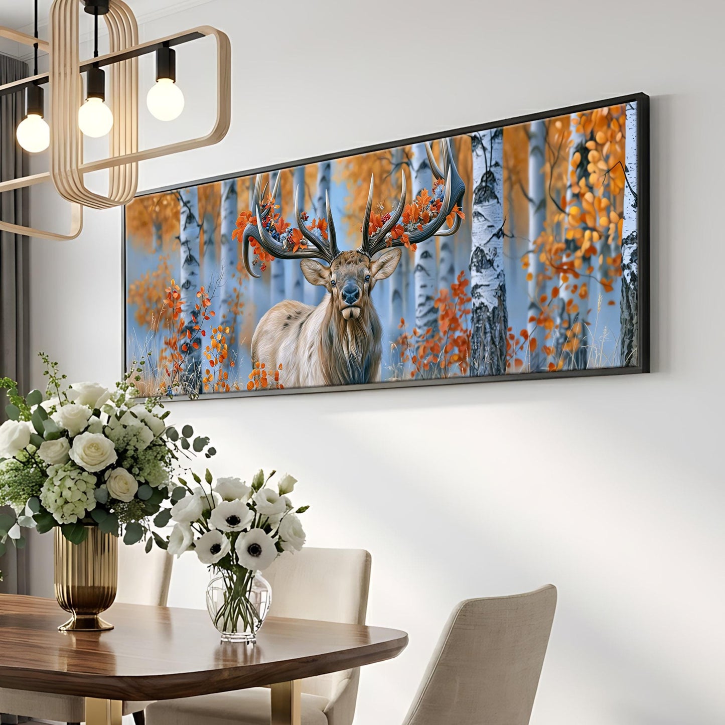 a large framed painting of a deer with antlers, hanging on a wall above a dining table with a vase of white flowers on it.