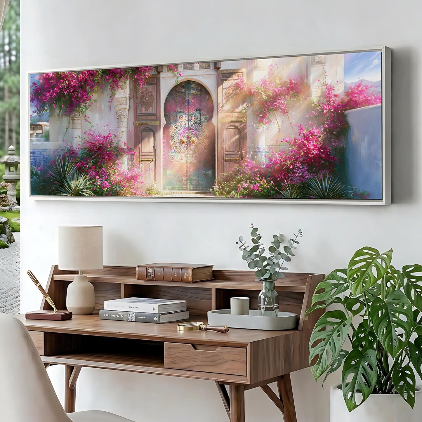 a large, colorful painting of a building with a vibrant garden in the foreground, hanging on a wall above a wooden desk with various items on it.