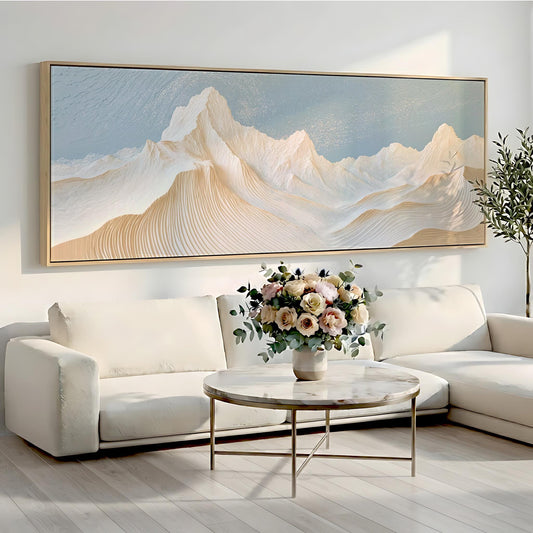 a living room with a large painting of a mountain landscape hanging on the wall above a white sofa. In front of the sofa, there is a round coffee table with a vase of flowers on it.