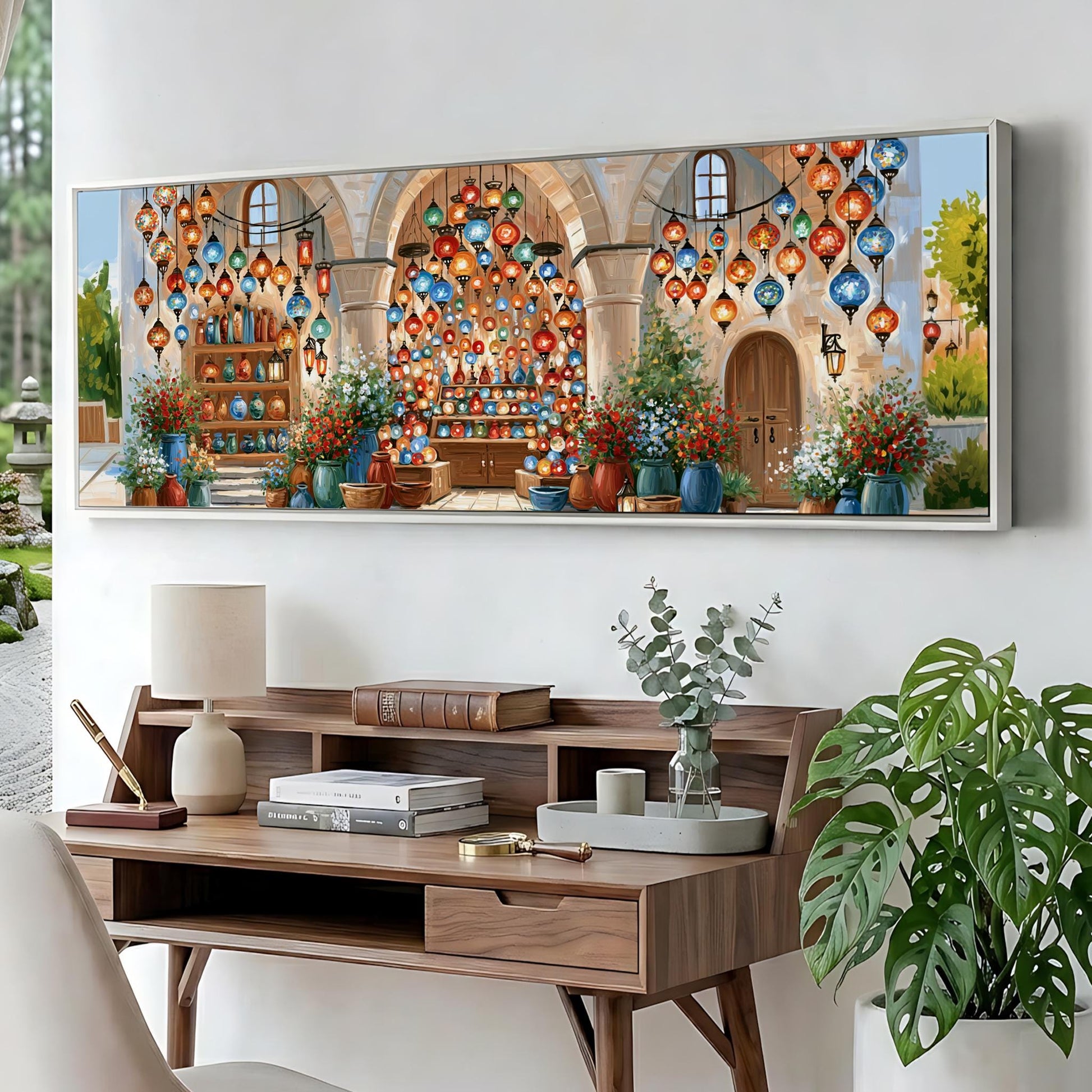 a large, colorful painting of a market scene with various items for sale, including potted plants, vases, and books. The painting is displayed on a wall above a wooden desk with a lamp, a plant, and some books.