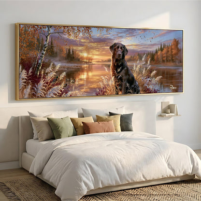 A large, framed painting depicting a serene landscape with a dog sitting in the foreground, surrounded by trees, bushes, and a lake at sunset.