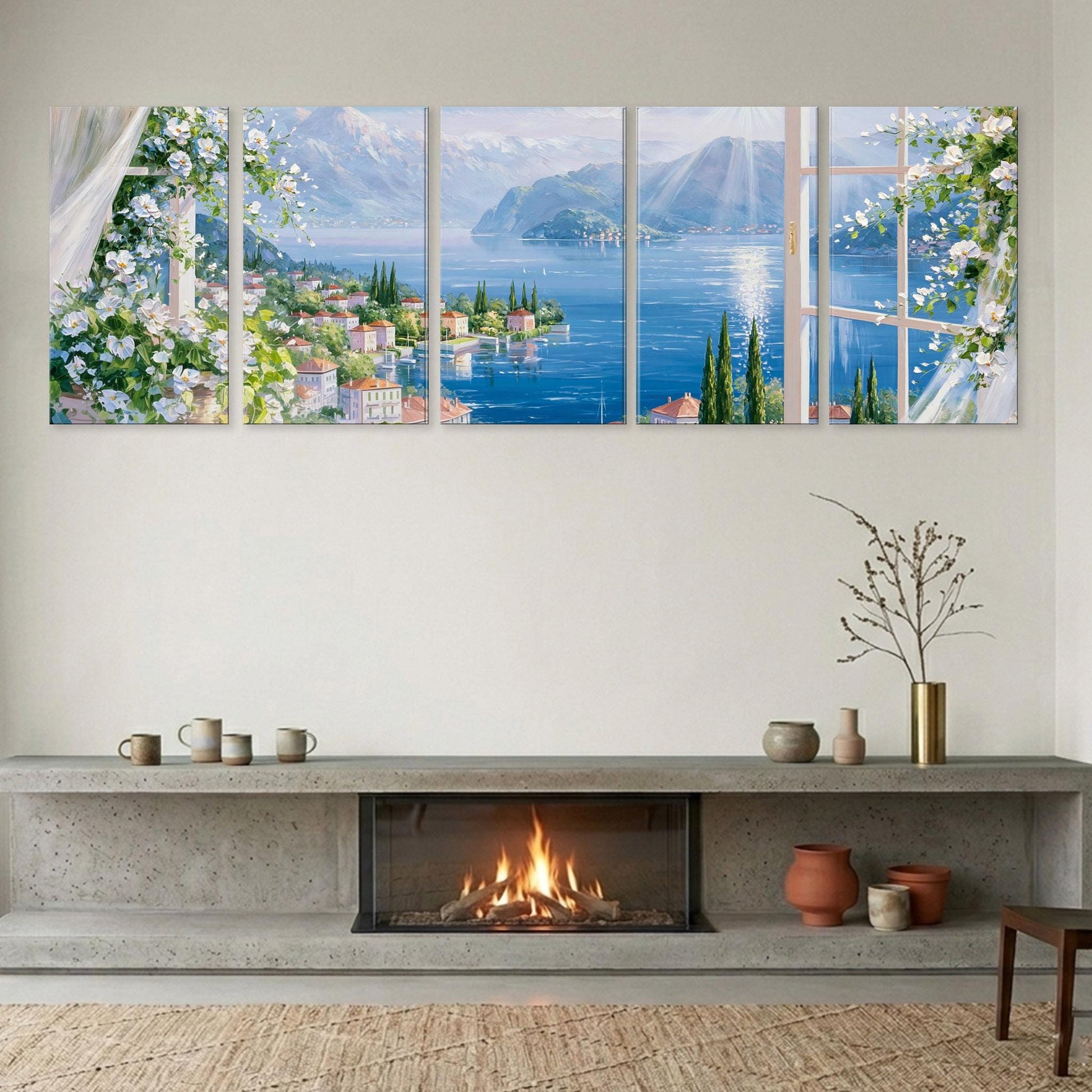 a cozy living room with a fireplace, a large window overlooking a picturesque lake and mountains, and a collection of five framed pictures arranged on the wall above the fireplace.