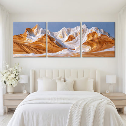 A large, three-panel landscape painting depicting a mountain range with a mix of orange and white hues, set against a clear blue sky.