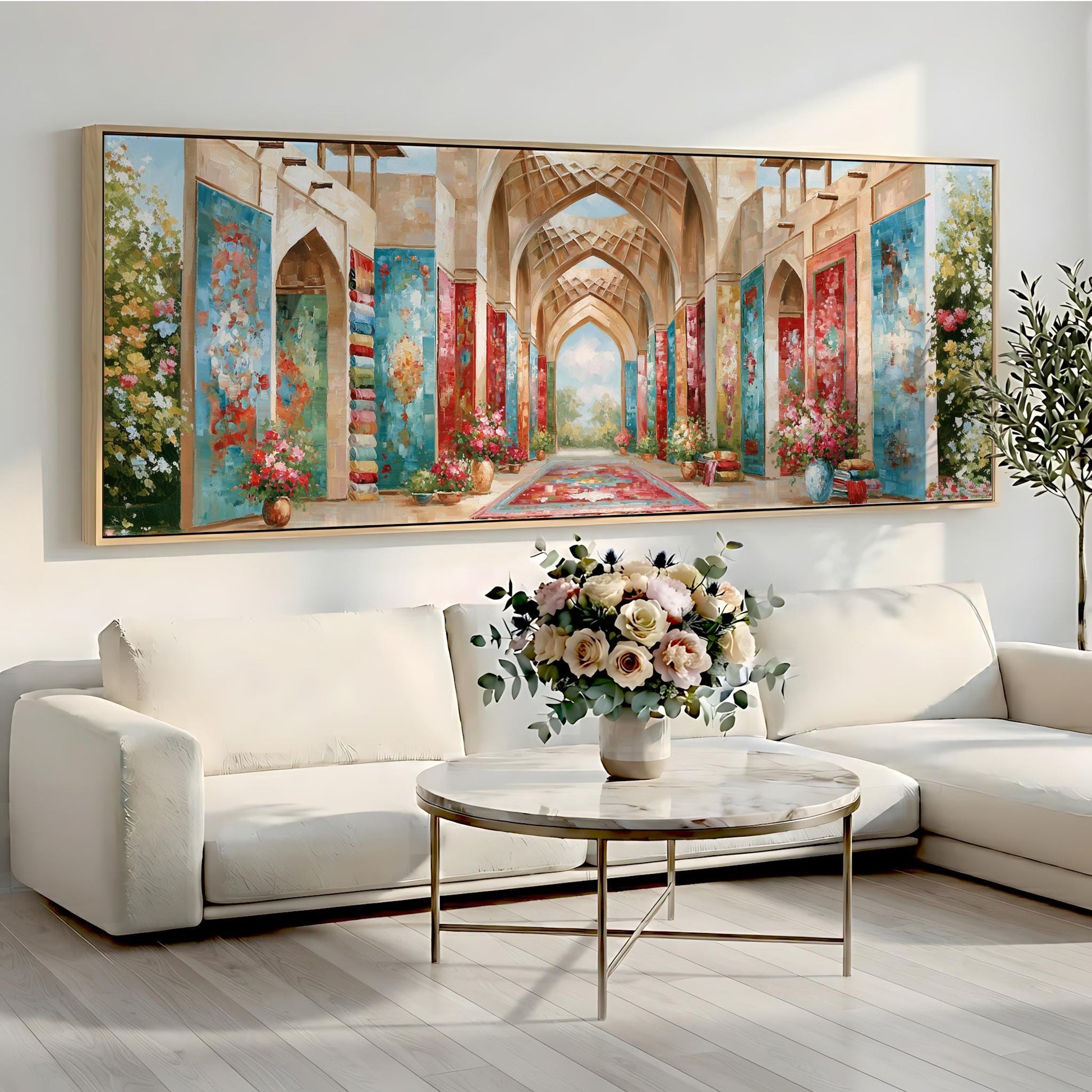 a large, colorful painting of an ornate hallway with arches and columns, hanging on a wall above a white sofa and a round coffee table with a vase of flowers.