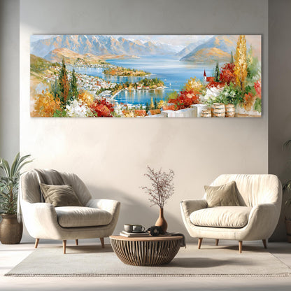 a large, colorful painting of a scenic landscape with mountains, a lake, and a town, hanging on a wall above a living room with two white armchairs and a coffee table.