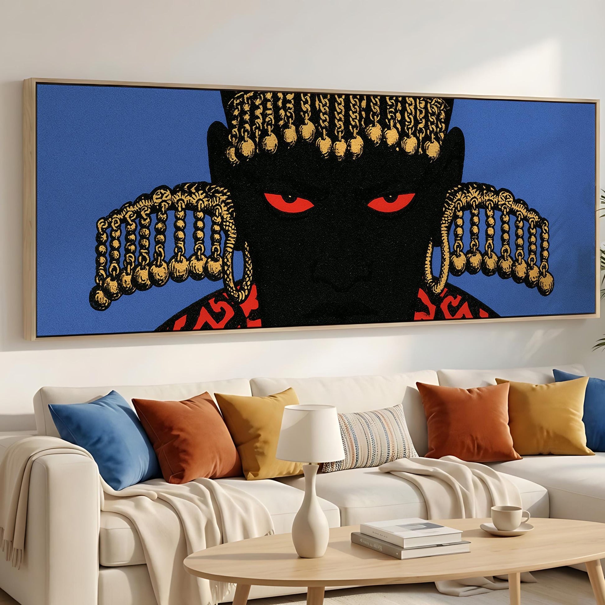 a large, colorful painting of a person's face with striking red eyes and gold accents, hanging on a wall above a white couch with colorful throw pillows.